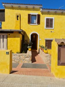 żółty dom z drzwiami i chodnikiem w obiekcie Santa Teresa - Verdemela w mieście Santa Teresa Gallura