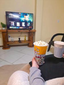 a person holding a cup of popcorn and a drink at Apartamento Cambara com churrasqueira e uma ampla sacada in Cambara do Sul