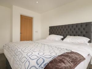 a bedroom with a large bed with a gray headboard at Atlantic Apartment in Bude