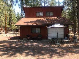 a red house with a table and an umbrella at Cheerful 2-Bedroom Cottage Near Eagle Lake in Susanville
