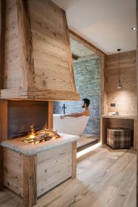un uomo in una vasca da bagno in un bagno in legno di Sci Sport rooms & suites a Bormio