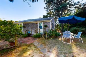 a small house with a blue umbrella and chairs at Beach Rose Guest Studio in Nauset Heights