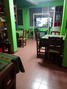 Habitación con paredes verdes, mesa y sillas. en HOSTEL JUJUY en San Salvador de Jujuy
