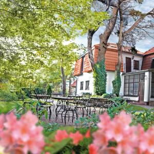 ヤストシェンビャ・グラにあるWilla Victorのテーブルと椅子、木々と花々が咲く公園