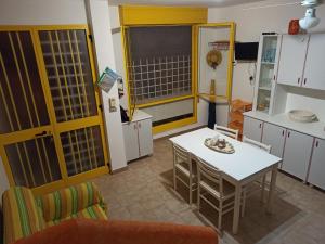 - une cuisine avec une table et une table et des chaises blanches dans l'établissement Casa Gialla, à Torre Pali