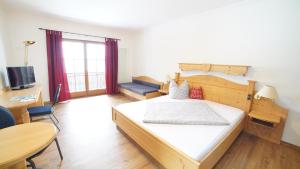 a bedroom with a bed and a desk and a television at Schliersberg Alm in Schliersee