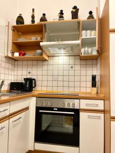 una cocina con armarios blancos y horno negro en Ruhiges Dachgeschoß CityApartment im Zentrum Wiens, en Viena
