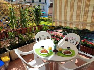 une table blanche avec deux assiettes de nourriture sur un balcon dans l'établissement Sea Garden, fronte mare con piscina, à Mascali