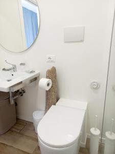 bagno bianco con servizi igienici e specchio di Dolce Dimora Charme Mare a Marina di San Vito