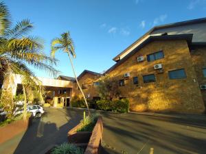 a building with a palm tree next to a parking lot at Suíça Hotel by Nordic in Foz do Iguaçu