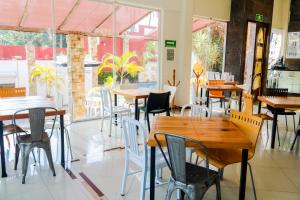 un restaurante con mesas y sillas de madera y ventanas en VF Villa Florencia Hotel en Veracruz