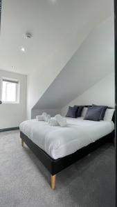 um quarto com uma cama grande com lençóis brancos e almofadas azuis em Lovely 2 Bed Apartment by YO ROOM- Leicester City- Free Parking em Leicester