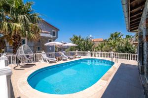 a pool with chairs and umbrellas next to a house at Villa Erya 2 in Fethiye