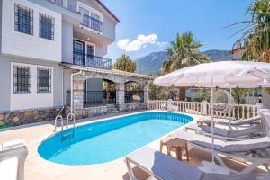 a villa with a swimming pool with chairs and an umbrella at Villa Erya 2 in Fethiye