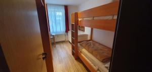 Pokój z 2 łóżkami piętrowymi i drzwiami w obiekcie Ferienidyll Langeoog w mieście Langeoog