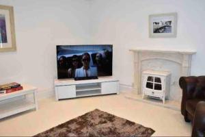 sala de estar con TV de pantalla plana y chimenea en Anglesey home by the sea en Amlwch