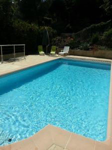 ein großer blauer Pool mit zwei Gartenstühlen in der Unterkunft Rose Niche in Cavalaire-sur-Mer