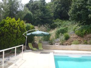 einen Pool mit einem Sonnenschirm, 2 Stühlen und einem Tisch in der Unterkunft Rose Niche in Cavalaire-sur-Mer