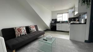 uma sala de estar com um sofá preto e uma cozinha em Lovely 2 Bed Apartment by YO ROOM- Leicester City- Free Parking em Leicester