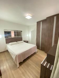 a bedroom with a white bed and wooden cabinets at 1810 - Flat para temporada em Goiania-proximo ao Parque Areião in Goiânia