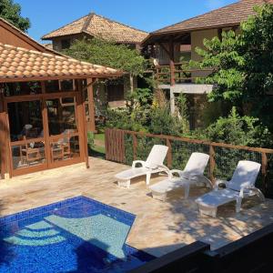 un patio avec deux chaises et une piscine dans l'établissement Pousada Morada Flor da Terra, à Guarda do Embaú