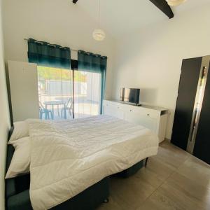 a bedroom with a bed and a kitchen with a table at Studio indépendant sur propriété avec piscine partagée in Biscarrosse