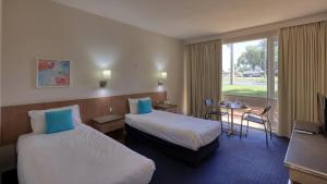 Habitación de hotel con 2 camas y mesa en Swan Hill Resort, en Swan Hill