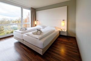a bedroom with two beds and a large window at Atlantic Hotel Galopprennbahn in Bremen
