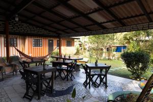 a patio with tables and chairs under a roof at Pousada Recanto das Cores in Ilha do Mel