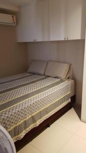 - un lit dans une petite chambre avec des armoires blanches dans l'établissement Apartamento confortavel com piscina em Intermares, à Cabedelo