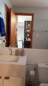 La salle de bains est pourvue d'un lavabo, de toilettes et d'un miroir. dans l'établissement Apartamento confortavel com piscina em Intermares, à Cabedelo