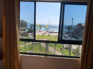 een raam met uitzicht op de oceaan vanuit een hotelkamer bij Hostal El Amigo in Paracas