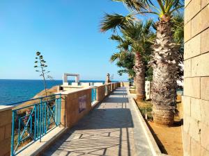 a walkway along the beach with palm trees and the ocean at Finestra sul Mare di Alessandro in Balestrate
