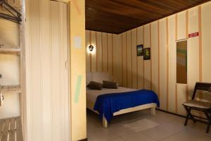a bedroom with a bed with a blue blanket at Pousada Recanto das Cores in Ilha do Mel