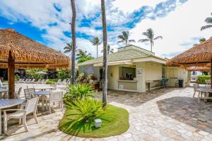 un patio con mesas, sillas y palmeras en Kauai Beach Villas E5, en Lihue