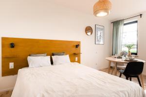 a bedroom with a large white bed and a table at Urban Condo in Liepāja