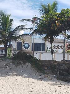 a building with palm trees in front of a beach at Pousada & Hostel Boca da Barra in Itanhaém