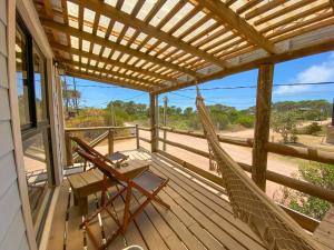 a porch with a hammock and a table and chairs at Mandalas de Mar in Punta Del Diablo