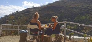 dos mujeres sentadas en una mesa frente a una montaña en Ecolodge Casa del Montañista en Huaraz