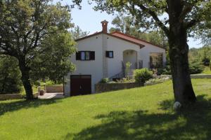 una pequeña casa blanca en una colina con árboles en Holiday house with a parking space Krsan - Vlasici, Central Istria - Sredisnja Istra - 7685, en Kršan