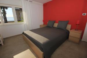 a bedroom with a bed and a red wall at Apartments with parking space Lovran, Opatija - 7705 in Lovran