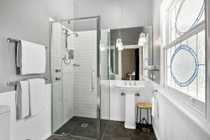 baño blanco con ducha y lavamanos en The Bundanoon Guest House, en Bundanoon