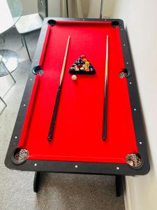 a red pool table with two cuesticks on it at Two Bedroom Entire Flat, Luxury but Affordable Next to M90 in Fife
