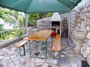 una mesa de picnic y bancos en un patio con chimenea en Studio Moscenice 7689b, en Mošćenička Draga