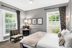 a bedroom with a bed and a chair and windows at The Bundanoon Guest House in Bundanoon