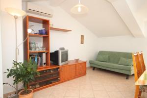 a living room with a tv and a green couch at Apartments with a parking space Medveja, Opatija - 7721 in Medveja