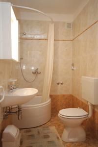 a bathroom with a toilet and a sink and a tub at Apartments with a parking space Medveja, Opatija - 7721 in Medveja