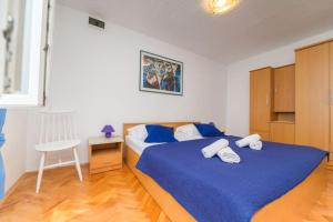 a bedroom with a bed with blue sheets and a chair at Apartments by the sea Nerezine, Losinj - 7963 in Nerezine