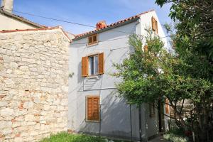 a white building with brown shutters and a tree at Holiday apartments Osor, Losinj - 8004 in Nerezine