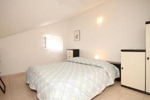 a white bedroom with a bed and a window at Holiday apartments Osor, Losinj - 8004 in Nerezine